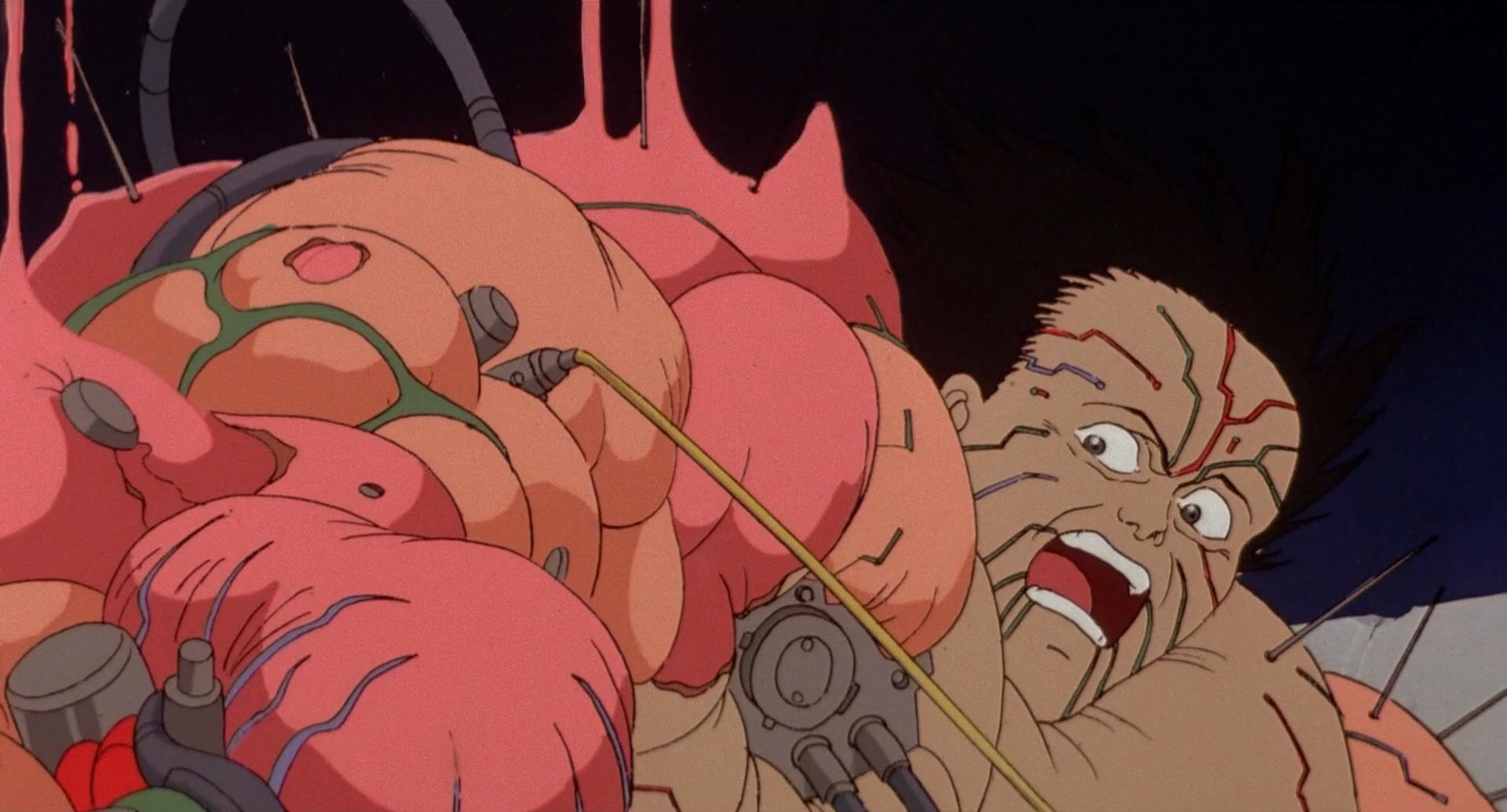 A still frame from the film Akira shows Tetsuo becoming mutated. His body balloons and wires and hoses protrude from his skin.